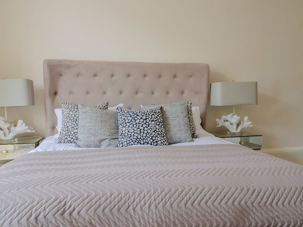 A bedroom featuring a bed with pillows and lamps at Saltwind Lyme Regis