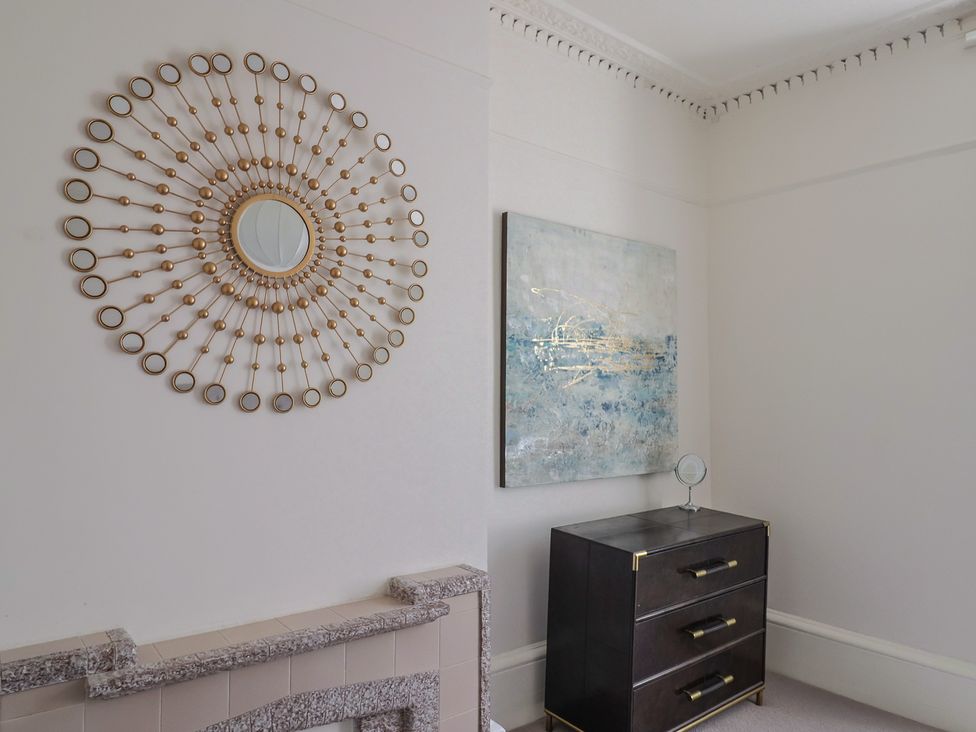 A bedroom with a mirror and artwork near a dresser at Saltwind in Lyme Regis