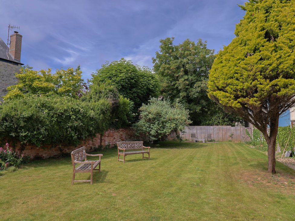 A garden with benches and trees at Saltwind in Lyme Regis