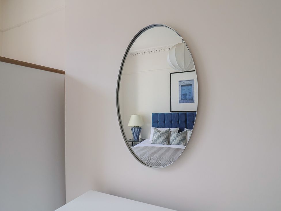 A bedroom with a mirror reflecting a bed and decor at Saltwind in Lyme Regis