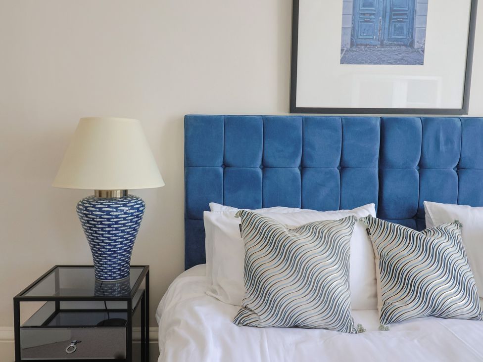 A bedroom with a blue headboard and lamp at Saltwind in Lyme Regis