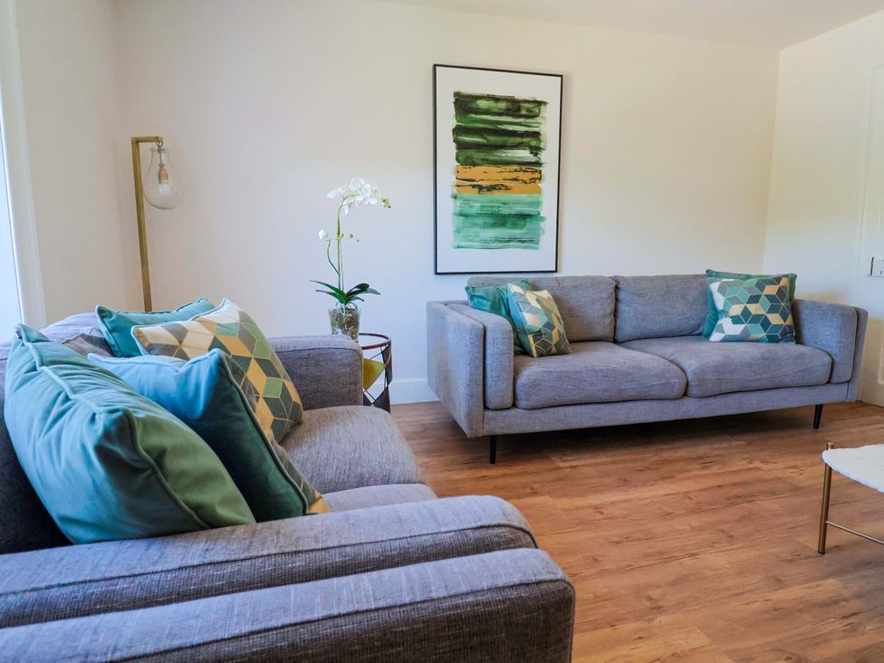 A living room with a sofa and wall art at Pebble Cove in Lyme Regis