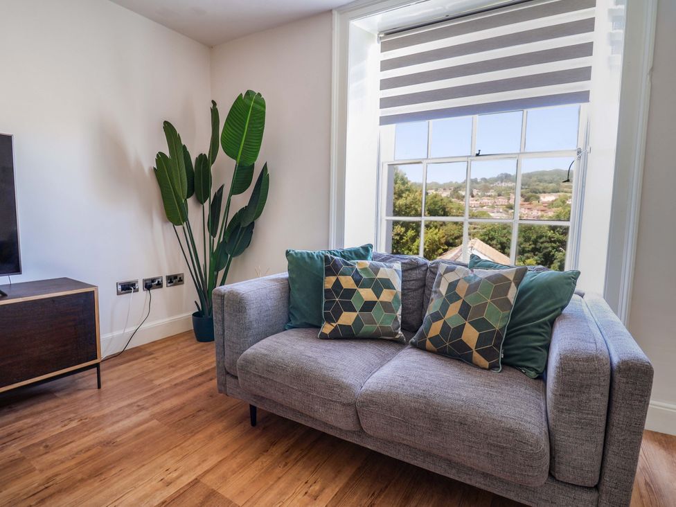 A living room with a sofa and plant at Pebble Cove in Lyme Regis