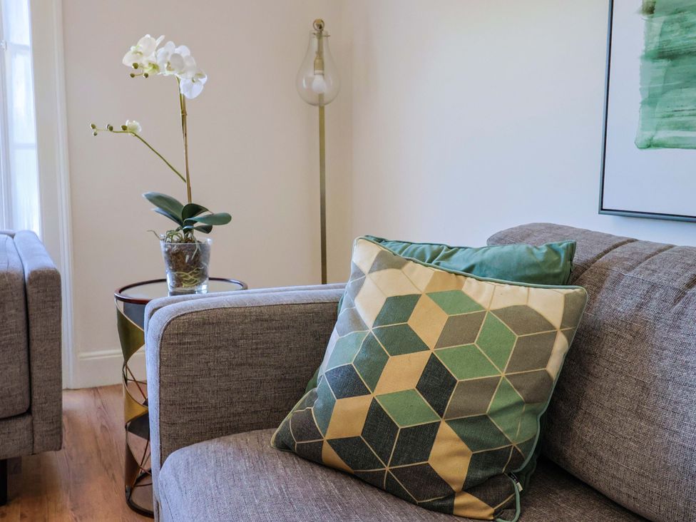 A living room with a couch, pillow, and plant at Pebble Cove in Lyme Regis