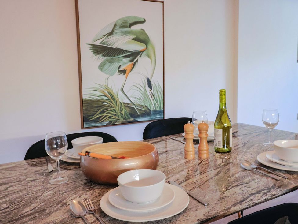 A dining table set with plates and a wine bottle at Pebble Cove in Lyme Regis