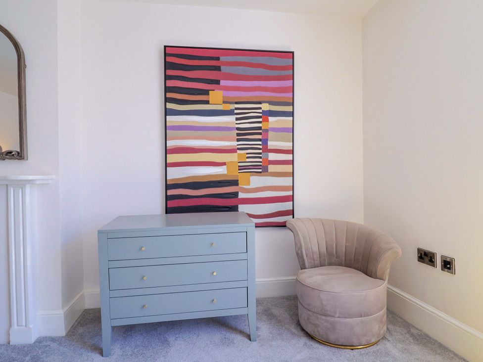 A living room with a decorative artwork and a chest of drawers at Pebble Cove in Lyme Regis