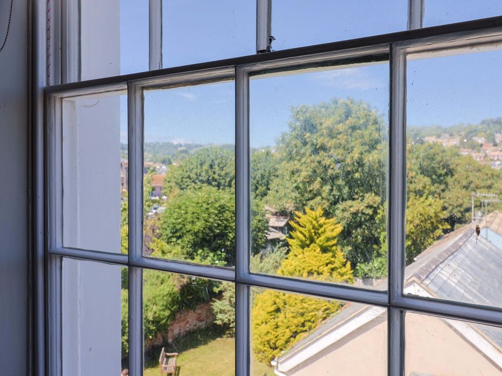 A window with a view of trees and a garden at Pebble Cove in Lyme Regis