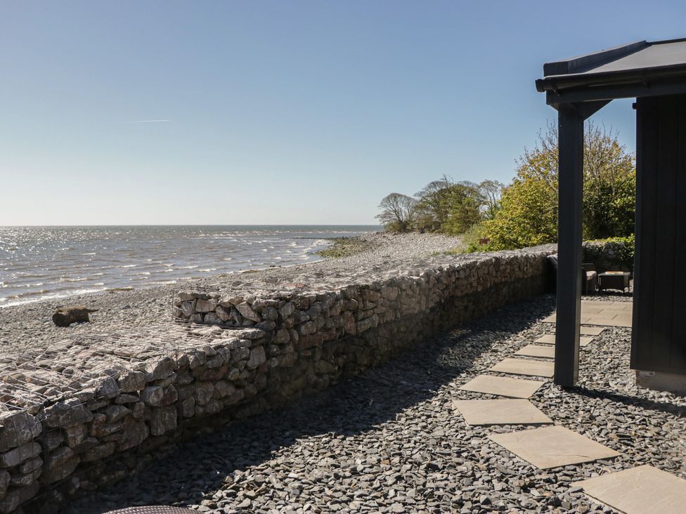 A view of the sea and shoreline with stones and a pathway at Driftwood Cottage in Ulverston