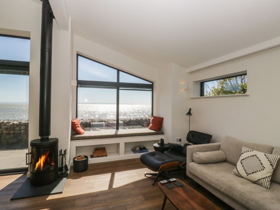 A living room with a wood stove and a sofa at Driftwood Cottage in Ulverston