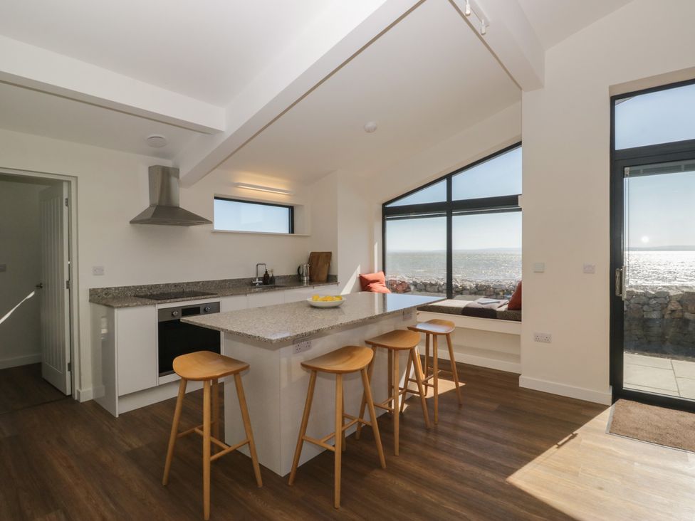 A kitchen with an island counter and bar stools at Driftwood Cottage in Ulverston