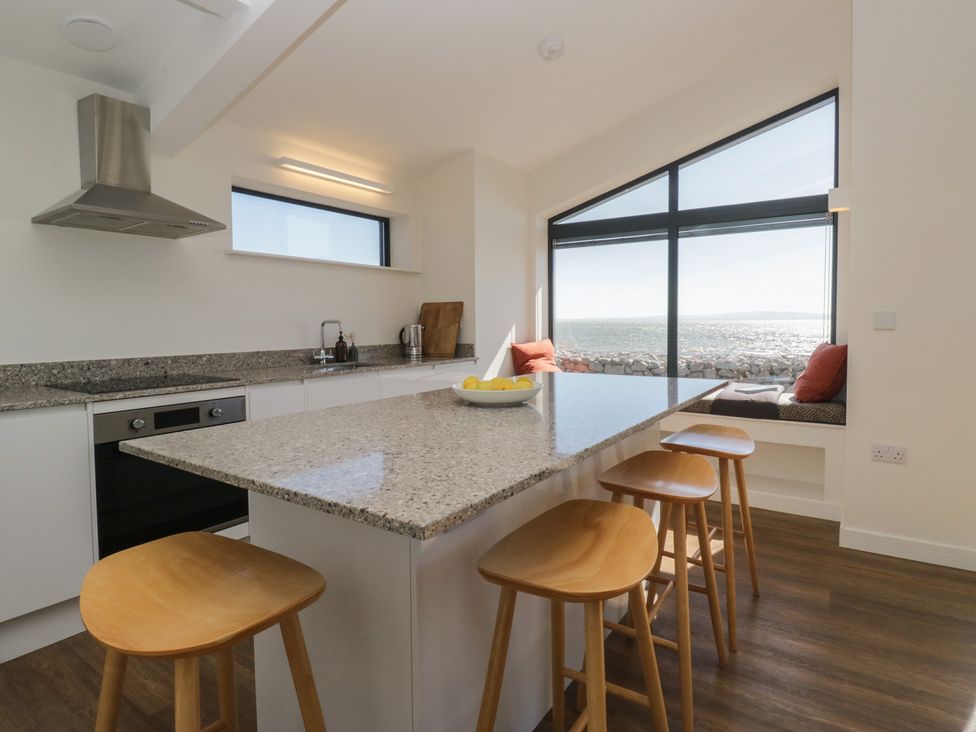 A kitchen with a countertop and bar stools at Driftwood Cottage in Ulverston