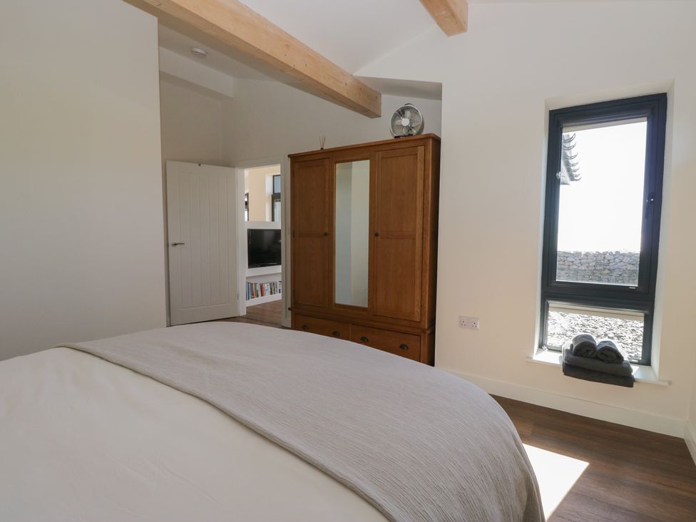 A bedroom with a bed and wardrobe at Driftwood Cottage in Ulverston