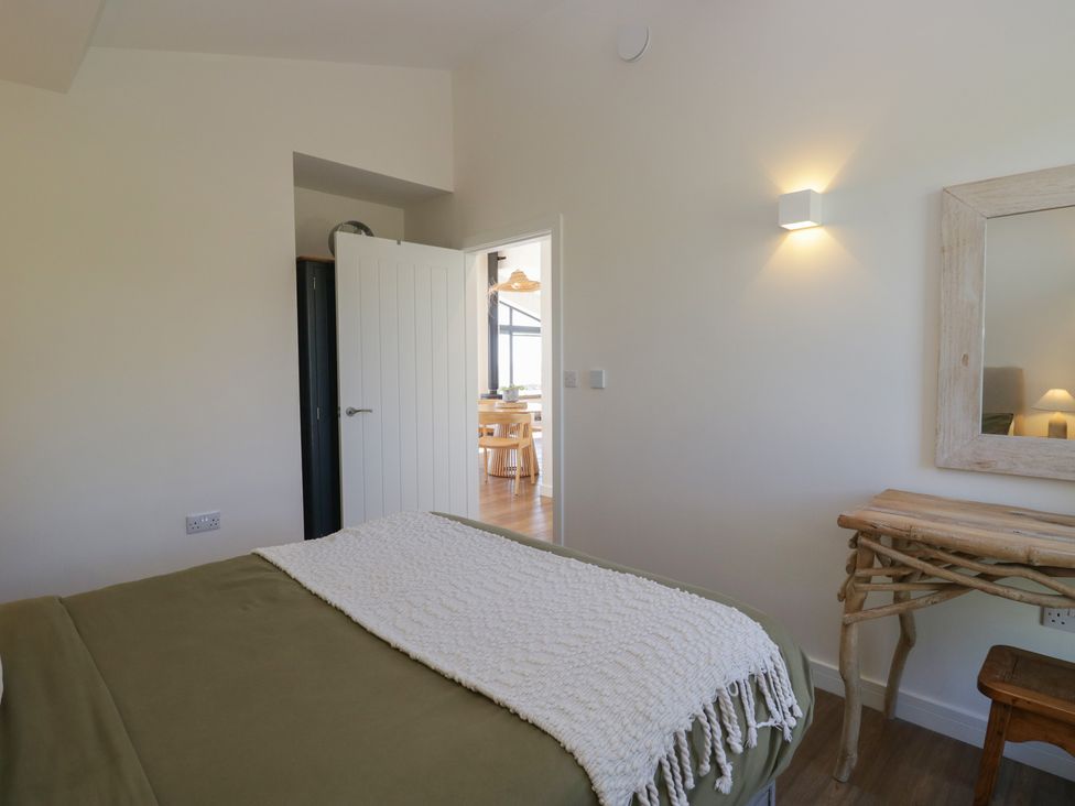 A bedroom with a bed and door leading to another room at Driftwood Cottage in Ulverston