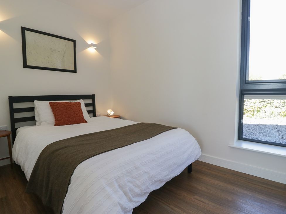 A bedroom with a bed and a side table at Driftwood Cottage in Ulverston