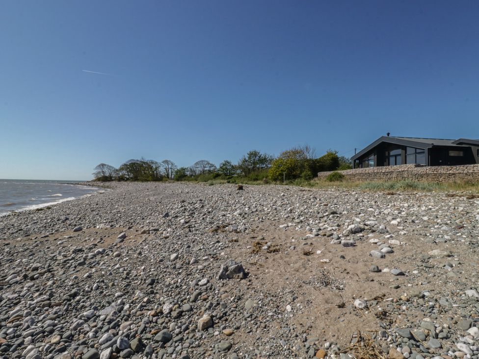 A beach with rocks and a house at Driftwood Cottage in Ulverston