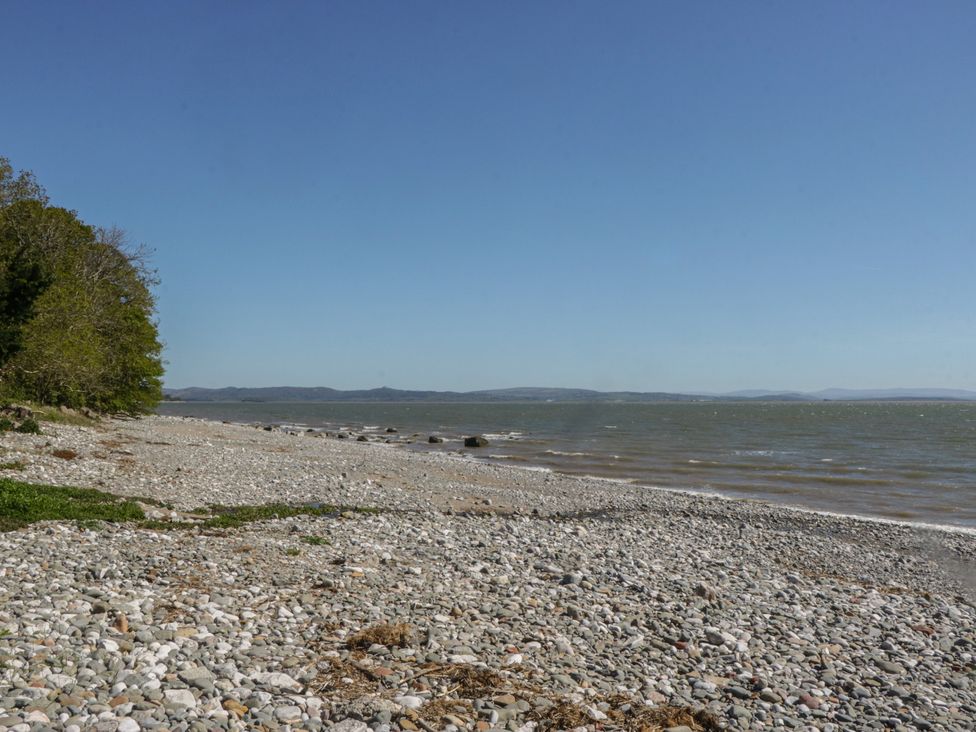 A rocky beach with water and trees at Driftwood Cottage in Ulverston