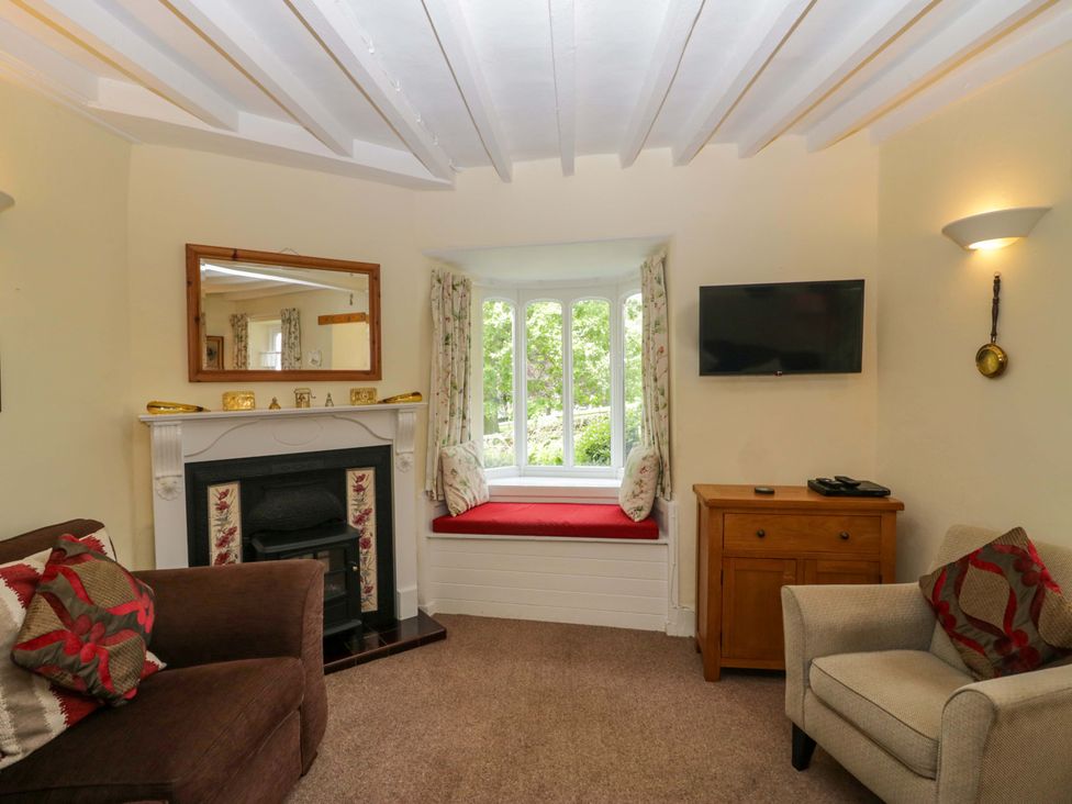 A living room with a fireplace and window seat at Hollens Cottage Grasmere