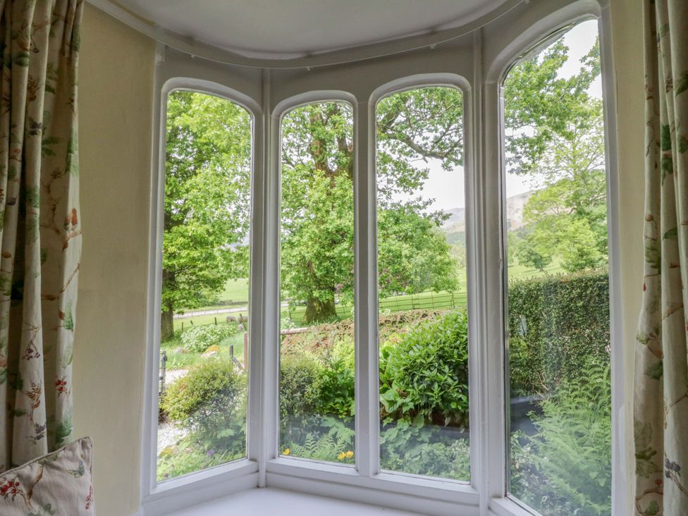 A living room window view of trees and garden at Hollens Cottage in Grasmere
