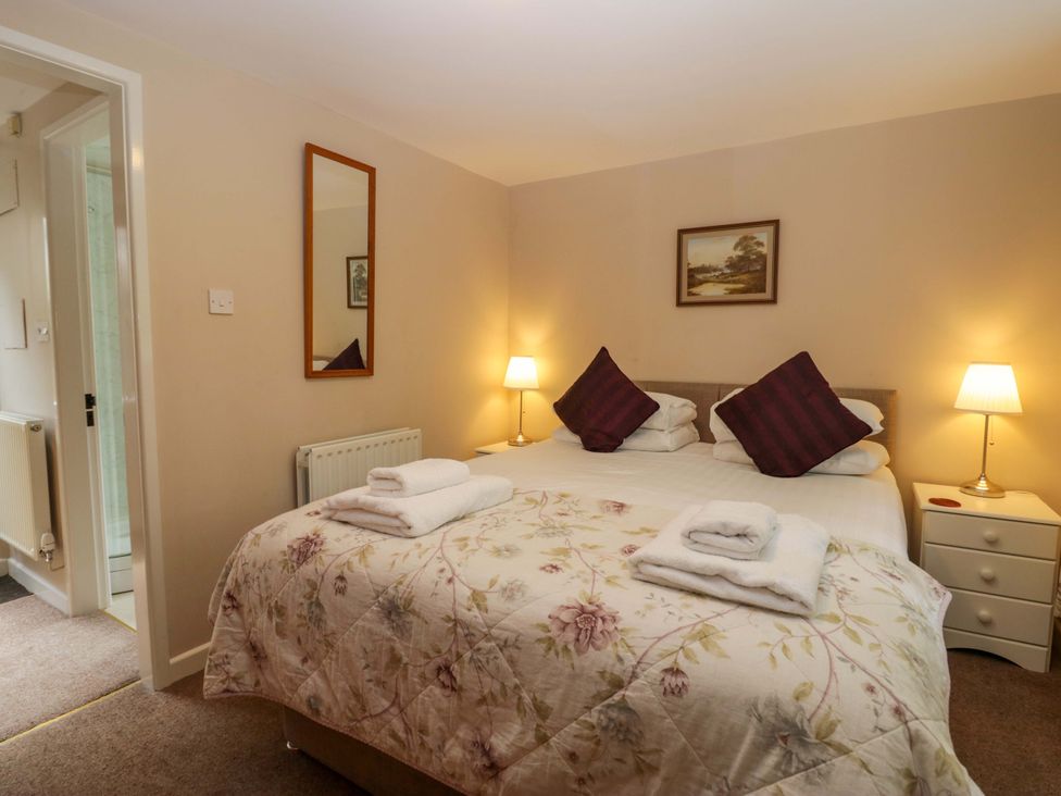 A bedroom with a bed and side tables at Hollens Cottage in Grasmere
