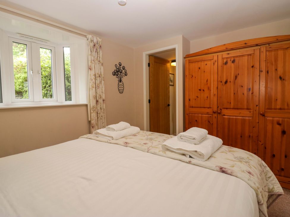 A bedroom with a bed and wardrobe at Hollens Cottage in Grasmere