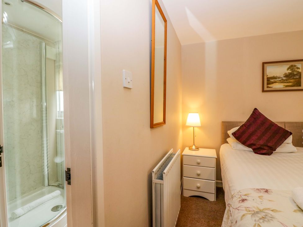 A bedroom with a bed and a shower in the corner at Hollens Cottage in Grasmere