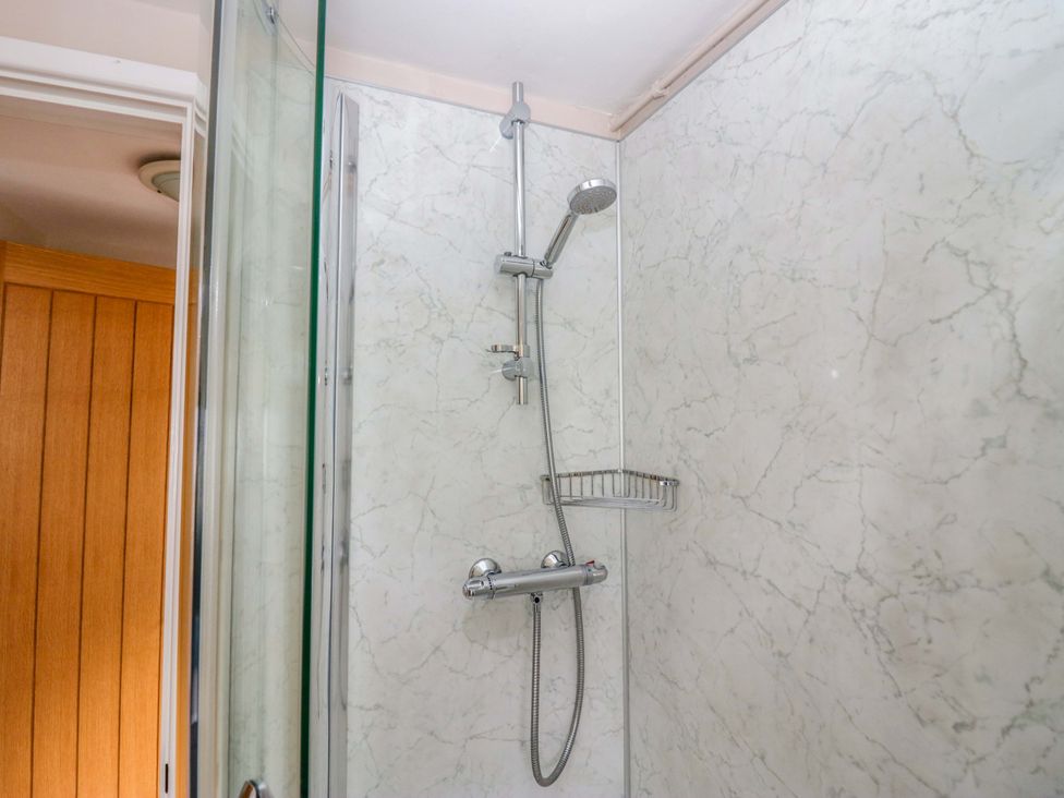 A shower with a chrome showerhead and control in a bathroom at Hollens Cottage Grasmere