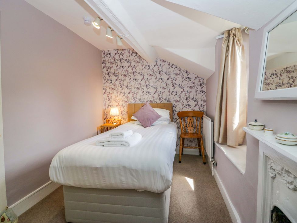 A bedroom with a single bed, chair, and lamp at Hollens Cottage in Grasmere