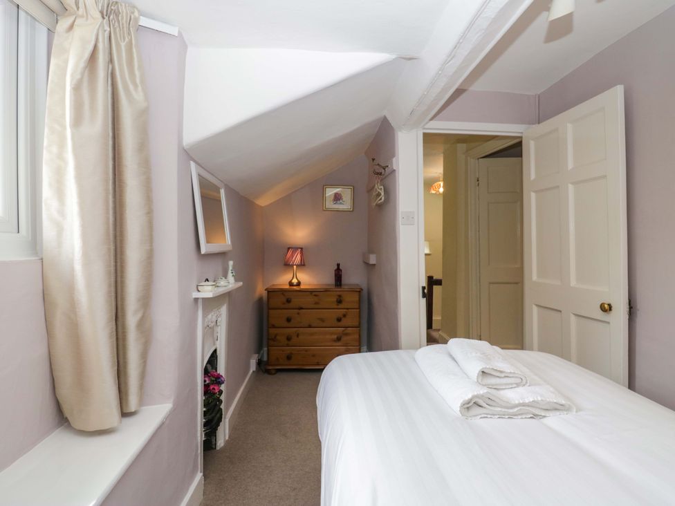 A bedroom with a bed and dresser at Hollens Cottage in Grasmere