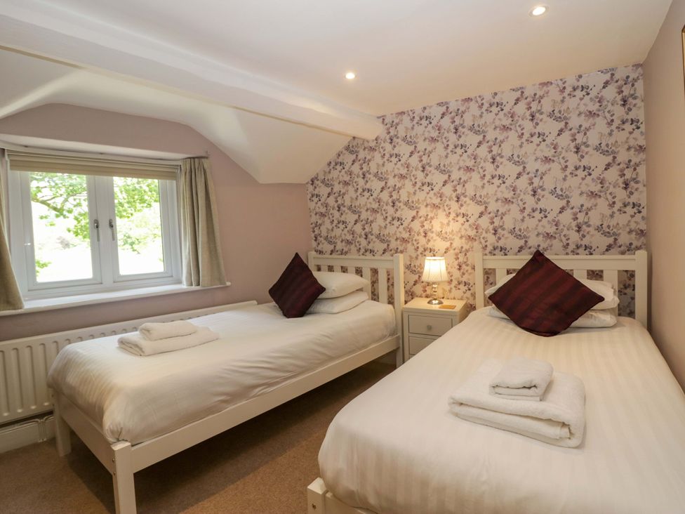 A bedroom with two beds and a window at Hollens Cottage in Grasmere