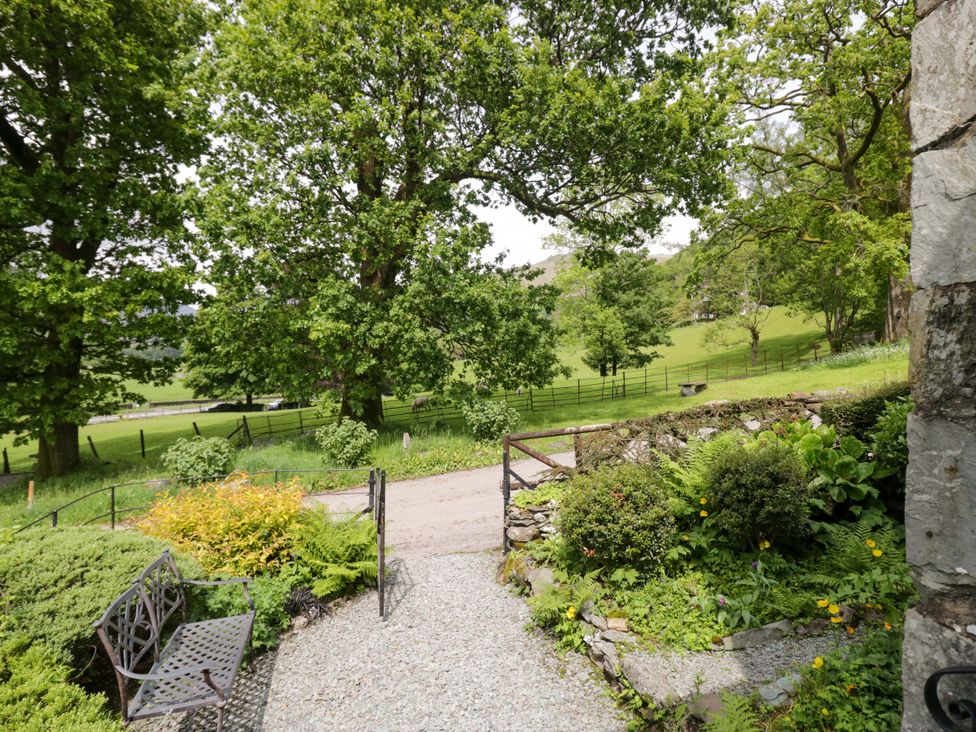 A garden view with trees and path at Hollens Cottage in Grasmere