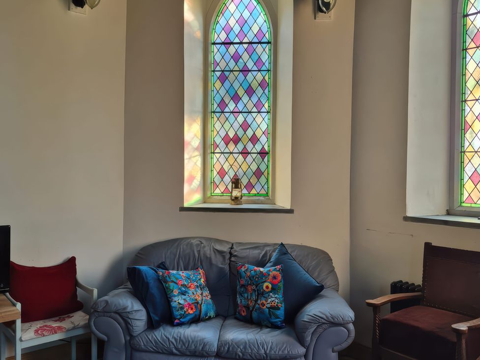 A sitting room with a sofa and stained glass windows at Church Llygad Y Dyffryn Sarnau near Brynhoffnant