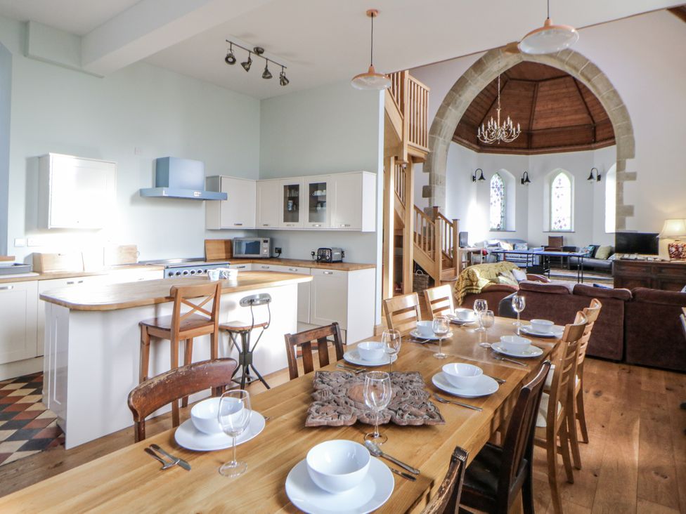 A kitchen and dining area with a table set for dinner at Church Llygad Y Dyffryn in Sarnau near Brynhoffnant