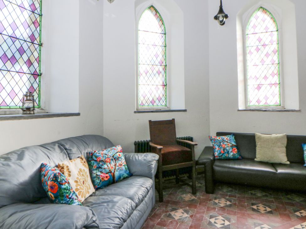 A snug area with a sofa and stained glass windows at Church Llygad Y Dyffryn Sarnau near Brynhoffnant