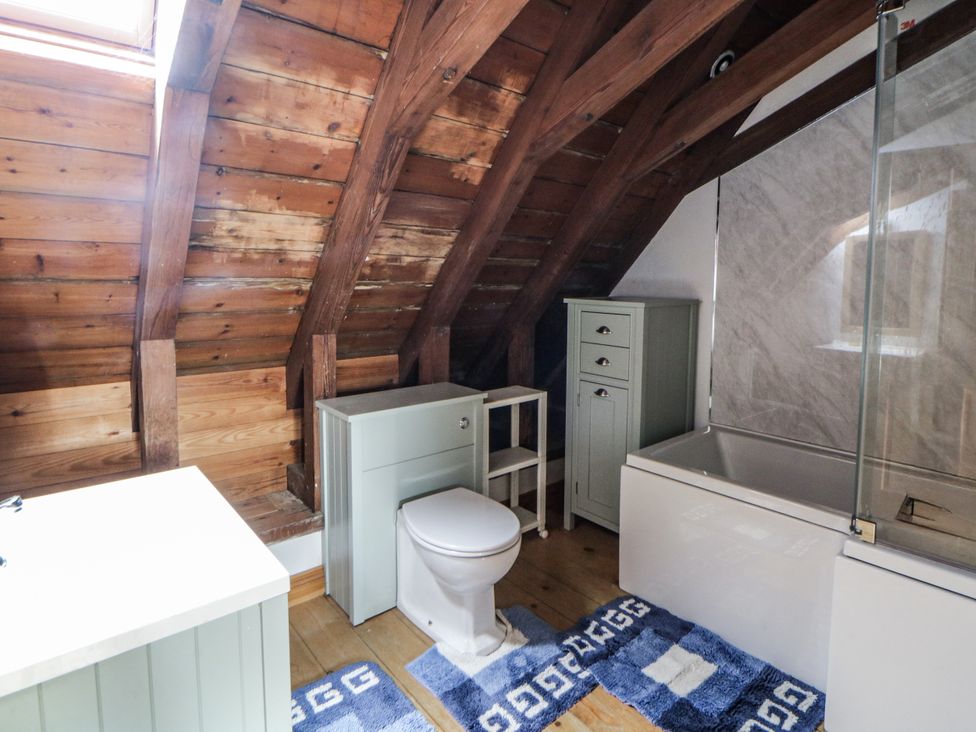 A bathroom with a toilet, bathtub, and storage cabinet at Church Llygad Y Dyffryn in Sarnau near Brynhoffnant