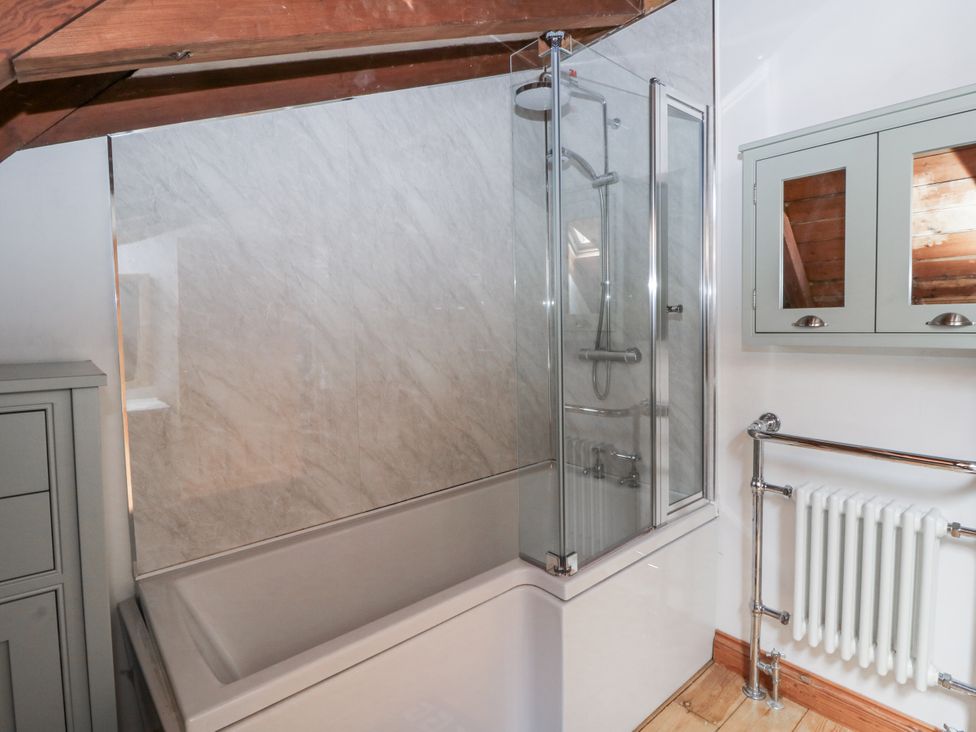 A bathroom featuring a bathtub, shower enclosure, and radiator at Church Llygad Y Dyffryn in Sarnau near Brynhoffnant