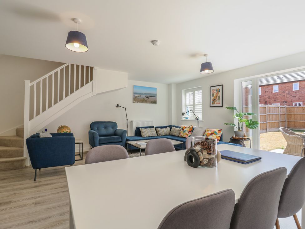 A living room with a sofa, armchair, coffee table and dining area at Inishnee House in Shotley Gate