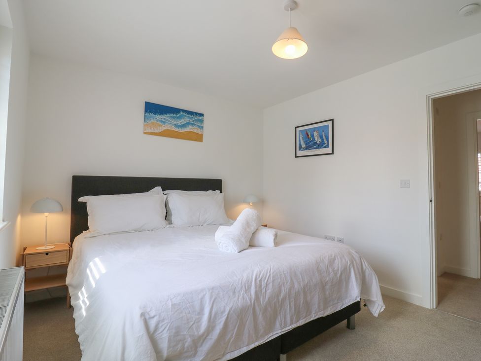 A bedroom with a bed, bedside table, and wall art at Inishnee House in Shotley Gate
