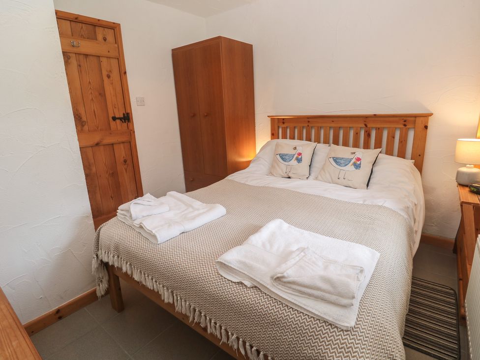 A bedroom with a bed and bedside table at Horseshoe Cottage Near Holywell Bay