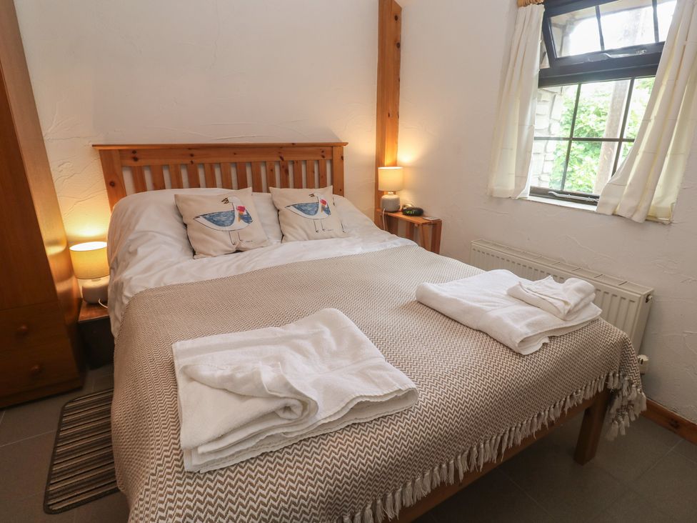 A bedroom with a bed and wardrobe at Horseshoe Cottage near Holywell Bay