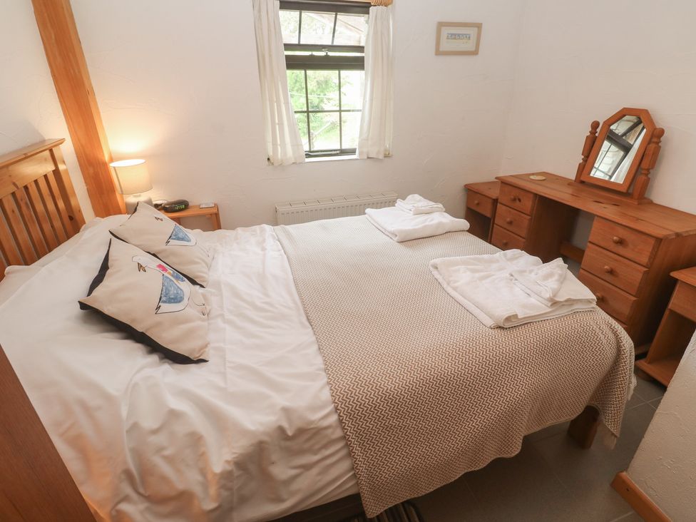 A bedroom with a double bed and dresser at Horseshoe Cottage near Holywell Bay