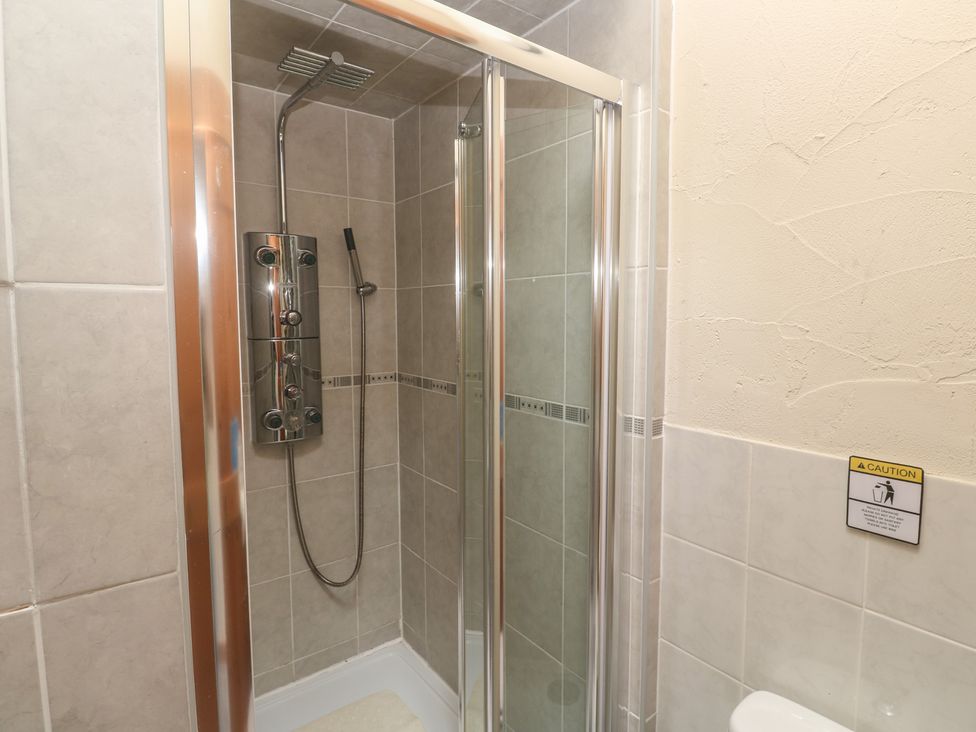 A shower with glass sliding door and controls at Horseshoe Cottage Near Holywell Bay