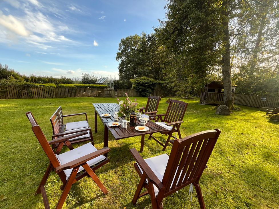 A garden with a wooden table and chairs at Pittencleroch Mill in Crieff