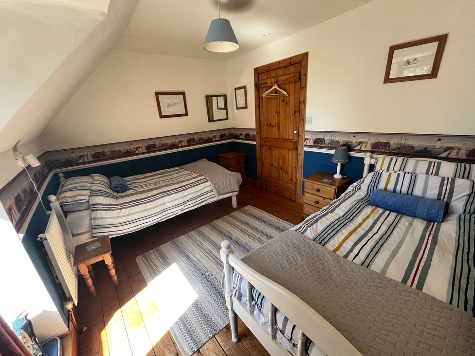 A bedroom with two beds and a wooden door at Pittencleroch Mill in Crieff