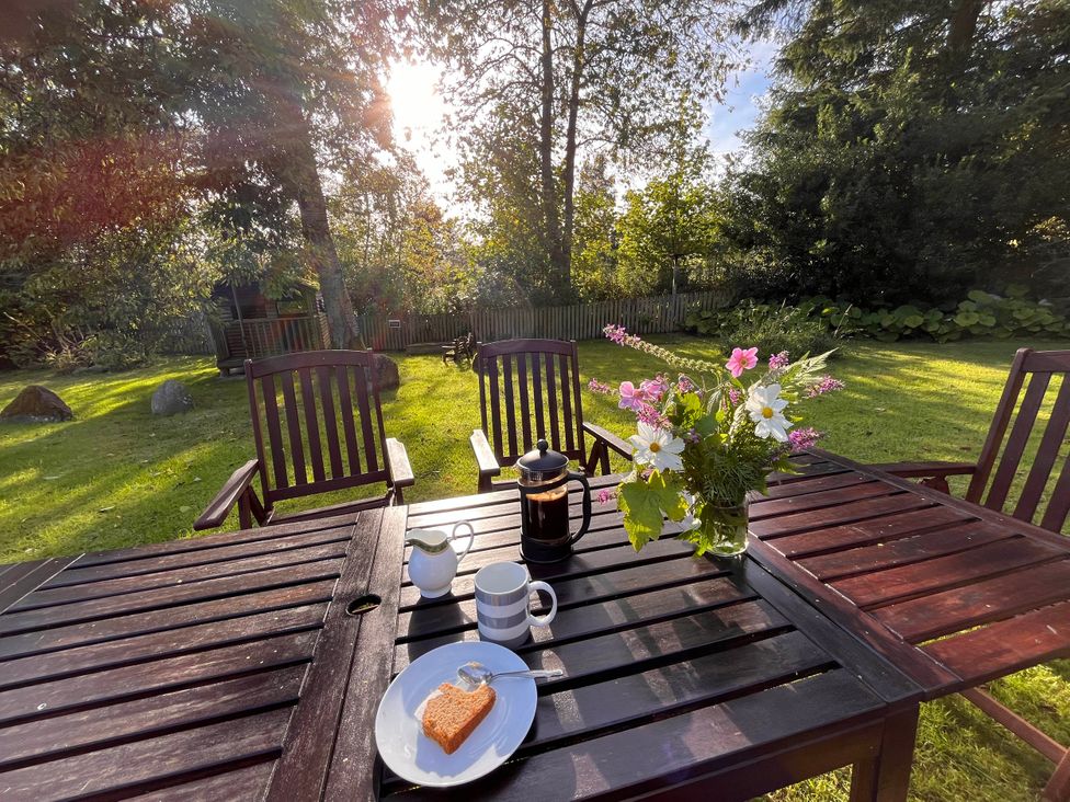 A garden table with coffee, cream, cake, and flowers at Pittencleroch Mill in Crieff