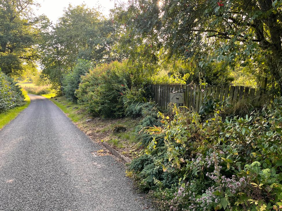 A road with vegetation and a sign at Pittencleroch Mill in Crieff
