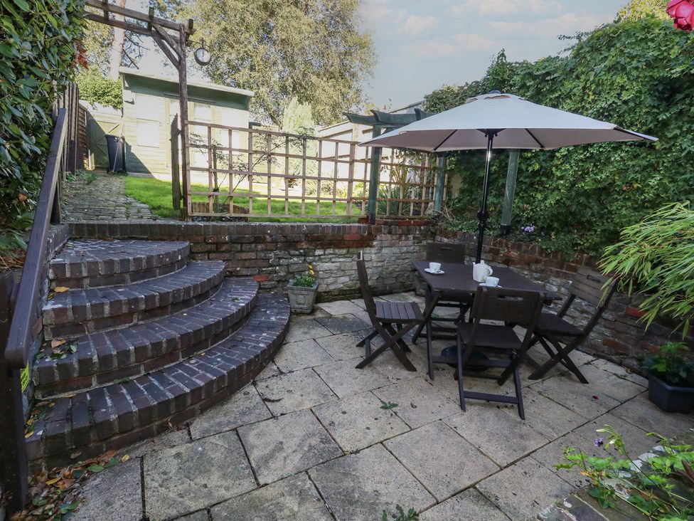A garden with a patio, table, chairs, and steps at Miller's Cottage in Puddletown
