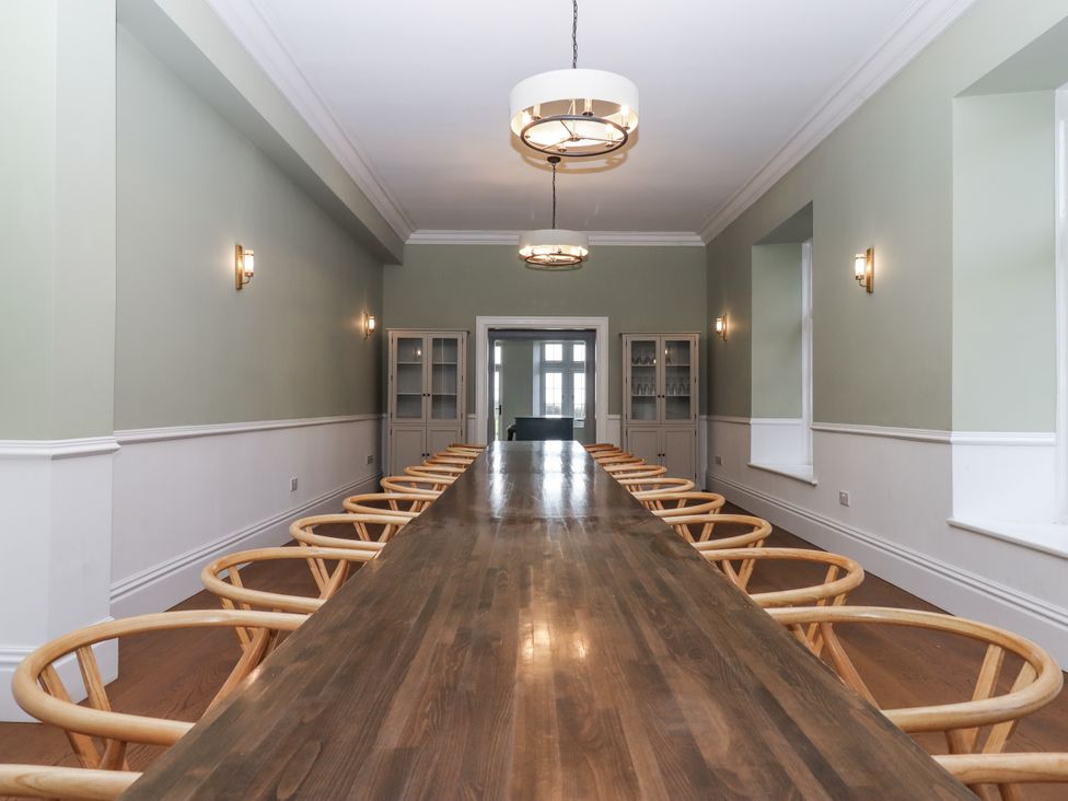 A dining room with a long table and chairs at Alston Hall Battisborough Cross