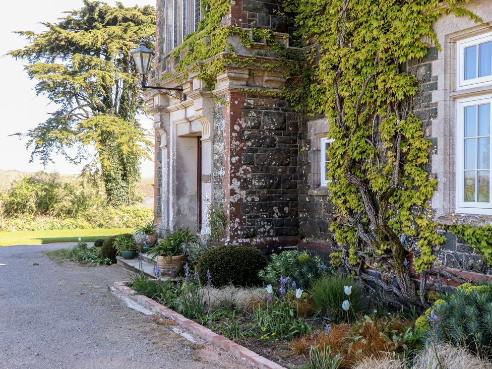 An outdoor area with a stone building and garden at Alston Hall near Mothecombe Beach