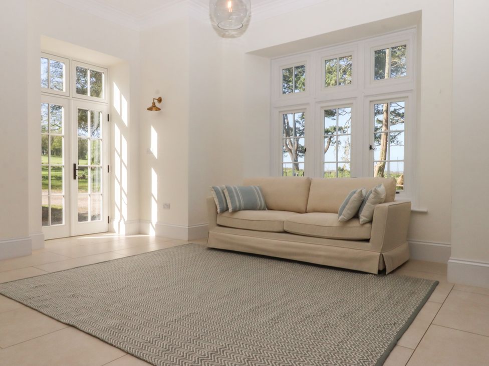 A living room with a sofa and windows at Alston Hall near Mothecombe Beach