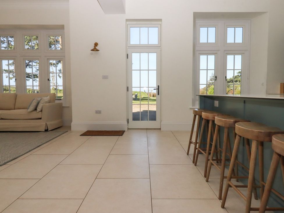 A kitchen with bar stools and a view at Alston Hall near Mothecombe Beach